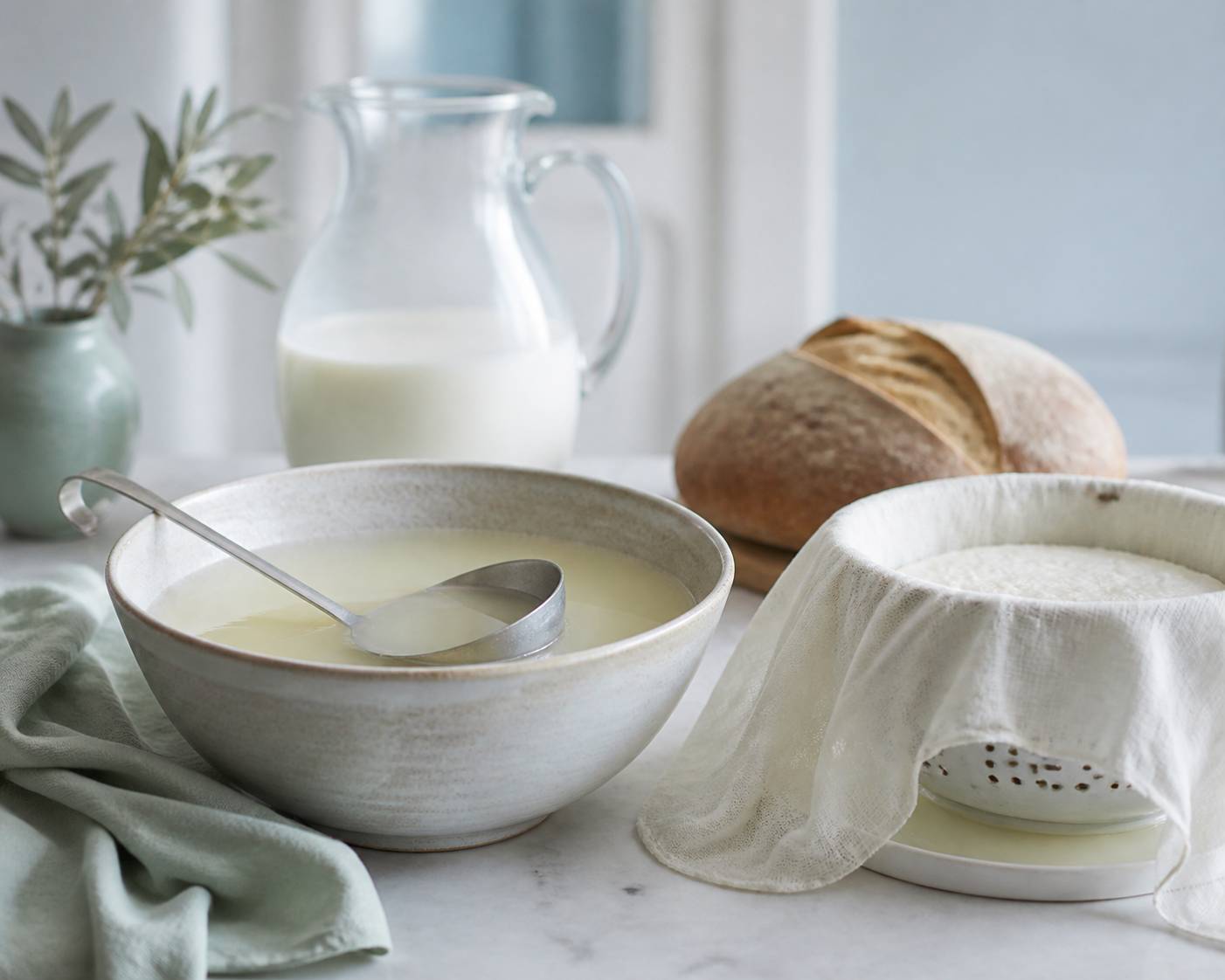 Bol de lactosérum avec faisselle et linge à fromage dans une cuisine de ferme
